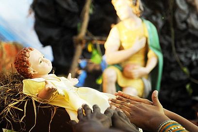 סרי לנקה. מאמינים מושיטים ידיים לבובת ישו התינוק (צילום: AFP)