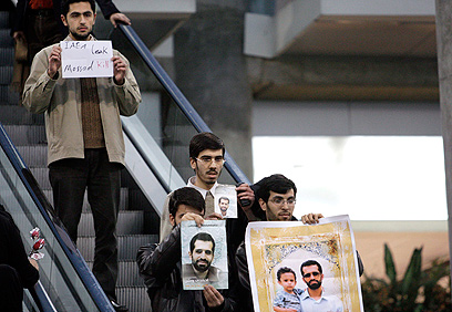 המפגינים עם תמונותיו של אחמדי-רושאן (צילום: AP)