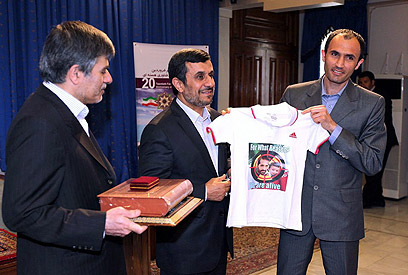 אחמדינג'אד עם חולצת המדען שחוסל (צילום: AFP PHOTO / HO/ IRANIAN PRESIDENCY WEBSITE)