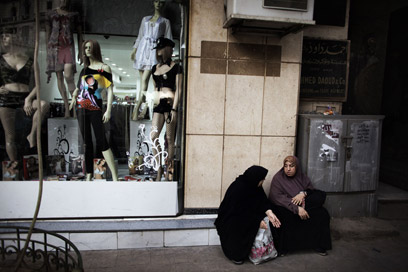נשים מצריות בלבוש מסורתי ליד חנות בגדים (צילום: AFP)