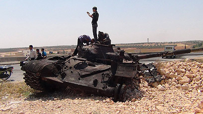 מורדים ליד טנקים שנפגעו באידליב (צילום: רויטרס)