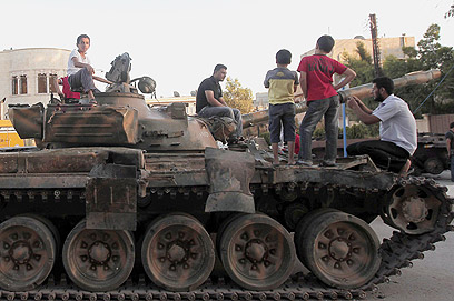 ילדים על טנק של צבא אסד בחלב (צילום: AFP)