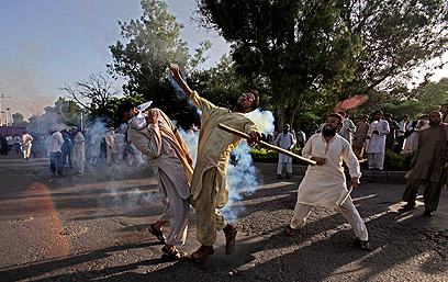 מפגין בפקיסטן זורק מכל גז מדמיע לעבר השוטרים (צילום: AP)