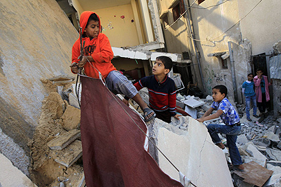 ילדים בעזה על הריסת מבנה שהותקף (צילום: AFP)