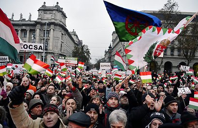 דגל צועני מונף בהפגנה נגד אנטישמיות בהונגריה (צילום: EPA)