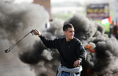 פלסטיני מיידה אבן בחברון, היום (צילום: AFP)
