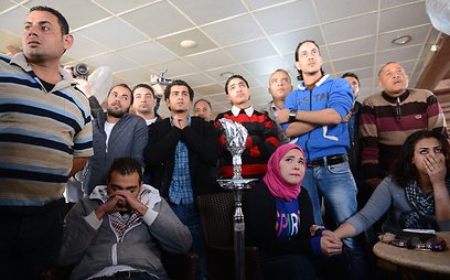 אזרחים בפורט סעיד צופים בטלוויזיה בהקראת גזרי הדין (צילום: AFP)