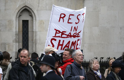 "נוחי על משכבך בבושה". שלט מחאה במסע ההלוויה (צילום: AFP)
