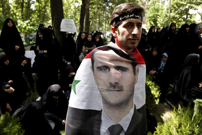 מפגין איראני עטוף בדיוקנו של אסד. הסכסוך מתפשט (צילום: AP)