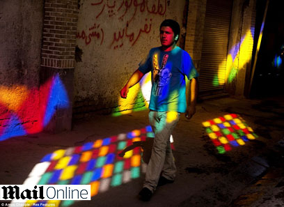 צעיר פוסע לאור הוויטראז'ים הצבעוניים בבזאר בטהרן