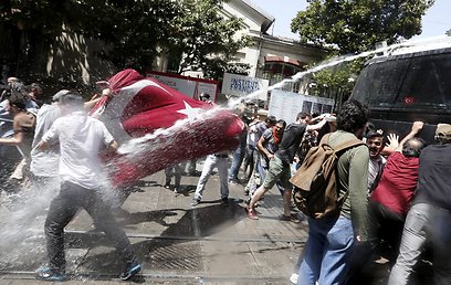תותחי המים של המשטרה מול הדגל הטורקי של המפגינים (צילום: EPA)